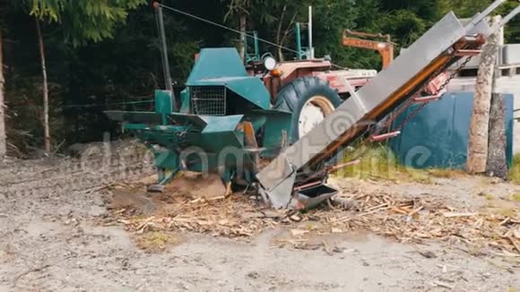村里的小锯木厂一台拖拉机和一个锯架在树林里旁边是切割和包装的原木视频的预览图