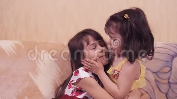 小女孩拥抱姐妹们互相拥抱孩子们正在沙发上玩耍穿裙子的女孩视频的预览图