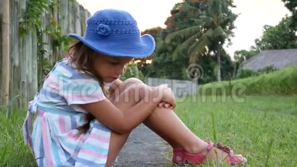 快乐的小女孩坐在草地上在夏天的花园里玩耍户外日落视频的预览图