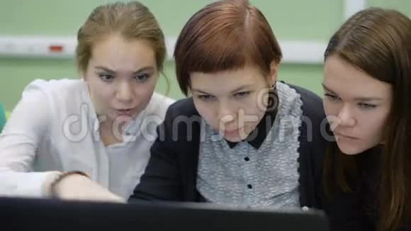 三个女生坐在书桌前看电脑屏幕视频的预览图