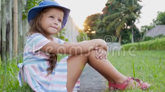 快乐的小女孩坐在草地上在夏天的花园里玩耍户外日落视频的预览图
