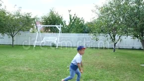 爸爸带着一个四岁的儿子在院子里的绿色草坪上踢球在夏天视频的预览图