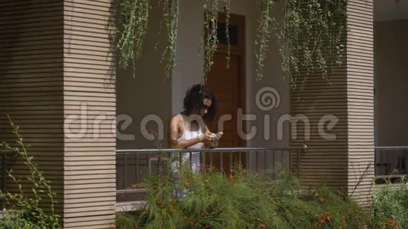 那个戴墨镜的黑发女孩站在大楼的阳台上靠在阳台上挂着一株植物视频的预览图