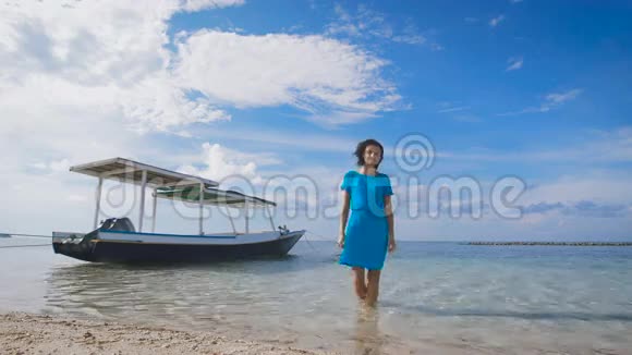 穿着绿松石服装的漂亮黑发女子站在大海中背景是传统的巴厘岛船适合视频的预览图