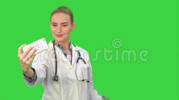 年轻漂亮的女医生在绿色屏幕上的智能手机上自拍Chroma键视频的预览图