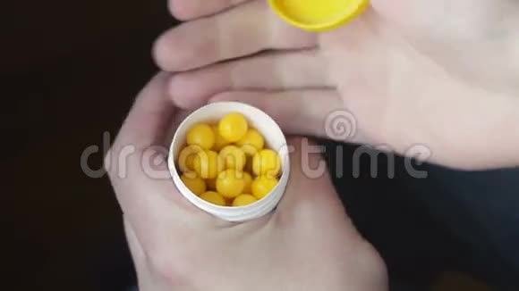 男人手里拿着一个白色聚合物药罐里面有黄色维生素在黑暗的背景上一个人视频的预览图
