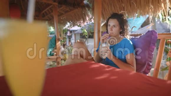 布吕内特短发坐在岛上一家咖啡馆的长凳上她很专注看着远处视频的预览图
