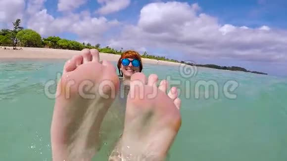 快乐兴奋的女人带着蓝色的眼镜在海洋中玩得很开心展示了她的腿和微笑慢动作热带岛屿视频的预览图