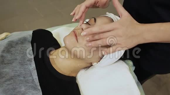 脸部按摩水疗皮肤和身体护理在美容院接受水疗按摩治疗的年轻女性的特写面部视频的预览图