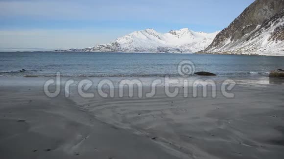 清冽的寒潮冲击着深秋浅棕色的沙质海岸带着雄伟的雪山背景视频的预览图