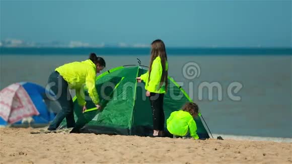 妈妈带着孩子在海滩上为家人准备帐篷视频的预览图