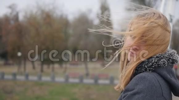 年轻的女孩站在街上她的头发在风中飘扬慢镜头视频的预览图