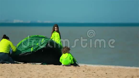 带着孩子的女人在海湾的岸边搭帐篷作为家庭度假视频的预览图