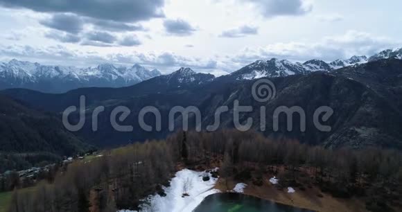 在乡村和蓝湖上方移动到松柏林和雪山秋天阿尔卑斯山户外自然视频的预览图