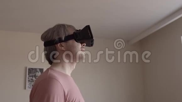 灰发男人在家玩他的手机虚拟现实耳机廉价的VR面具在行动4Ksteatam视频的预览图