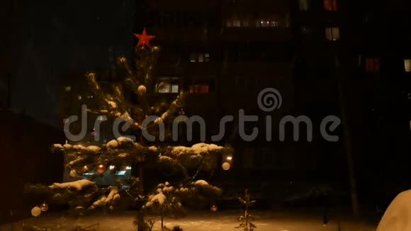 夜晚一棵装饰好的圣诞树矗立在街道上降下一场雪头顶上是一颗红星视频的预览图