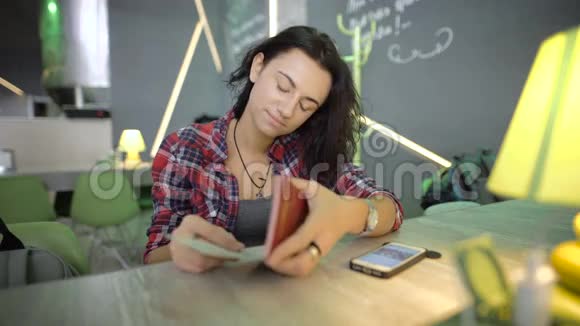 小女孩一头乌黑的短发穿着一件衬衫放在手表上坐在机场咖啡店的酒吧里视频的预览图