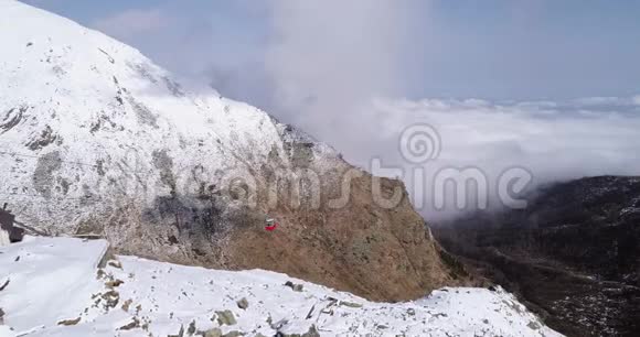 空中飞越雪山岭谷带云红缆车提立者户外冰雪高山野生视频的预览图
