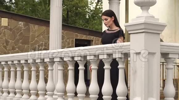 优雅的女孩倚在阳台的老栏杆上视频的预览图