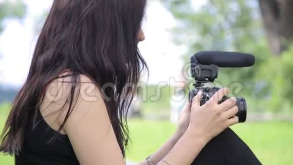 年轻的混血女独立电影制作人在绿色的自然环境中拍摄背景草视频的预览图