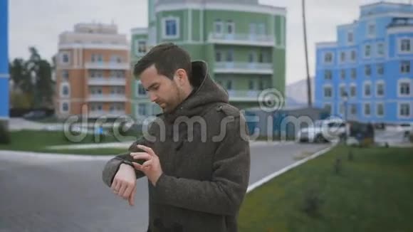 庭院房子一个穿着灰色外套手上拿着钟手指上戴着戒指的人在路上他改变了视频的预览图