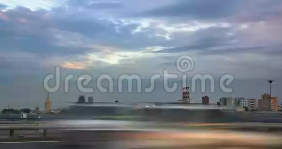 日落时分随着云层和各种建筑物在背景下的移动以及高速公路上的汽车交通时间流逝的城市景观视频的预览图
