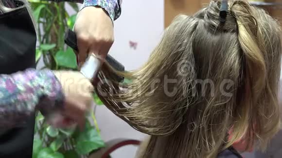 专业的女理发师用剪刀剪金发4K视频的预览图