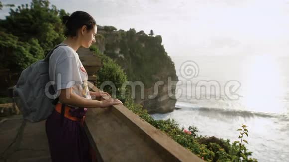 女游客站在山顶俯瞰海洋和悬崖女孩正看着视频的预览图