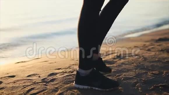 穿着运动鞋在沙滩上行走的女人腿的特写镜头视频的预览图