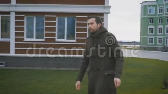 秋天天气里一个穿着灰色外套的人走在人行道上在城市的背景下五颜六色的房子视频的预览图