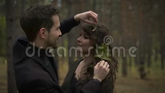 黎明时分在森林里相爱的一对夫妇年轻人拥抱他的女朋友玩弄她的头发他带着一个视频的预览图