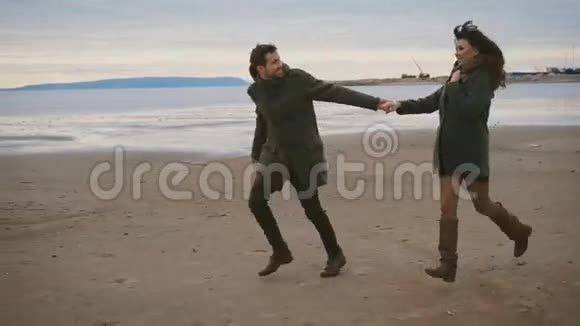 浪漫的一对夫妇一起在海滩上奔跑跳跃在海滨约会丈夫穿着外套视频的预览图