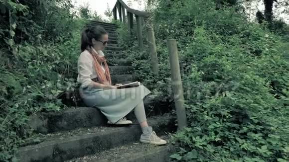 译文美丽的女孩坐在深绿色的森林里的岩石楼梯上靠近山河满足新鲜的空气和新鲜的空气视频的预览图