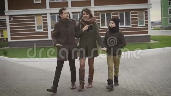 穿灰色外套的男人他的妻子和孩子在科蒂亚德他们去他家的院子里家庭散步爱情阳光视频的预览图