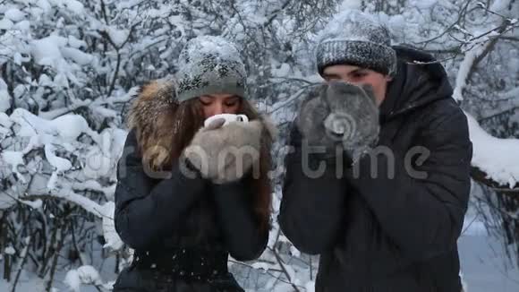 冰冻的漂亮女孩和一个热茶温暖的男人冬天公园里白雪覆盖了树木视频的预览图