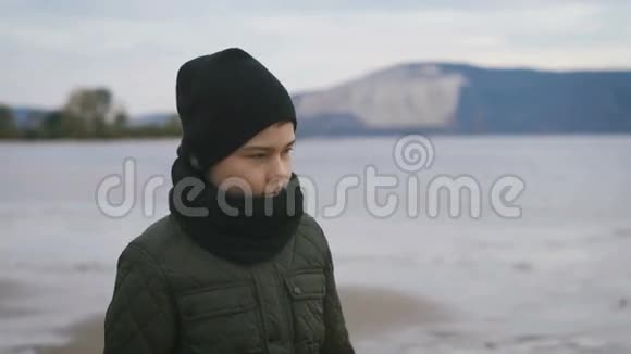 人行道美丽的大海迷人的山低波海滩上的一个男孩它温暖的夹克帽子围巾裤子视频的预览图