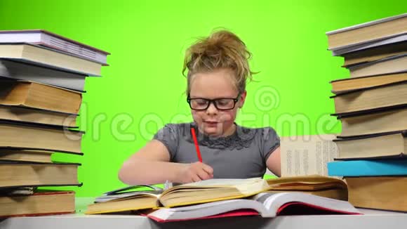 小女孩坐在桌子旁紧张地扔书绿色屏幕视频的预览图