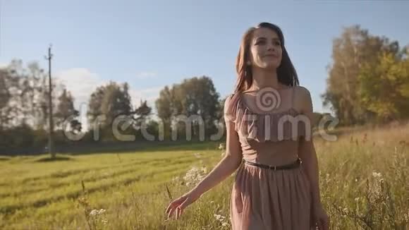美丽的长发女孩在绿色的草地上抚摸着花朵旋转享受视频的预览图