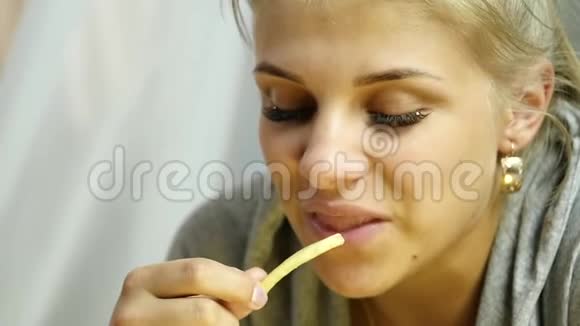 年轻女人吃炸薯条快速和垃圾食品的概念慢动作视频的预览图