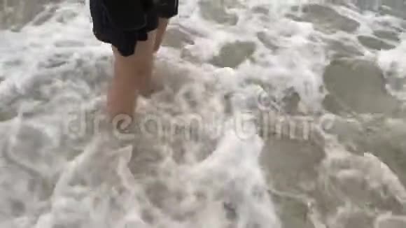 女孩的双脚站在海滩上海浪拍打视频的预览图