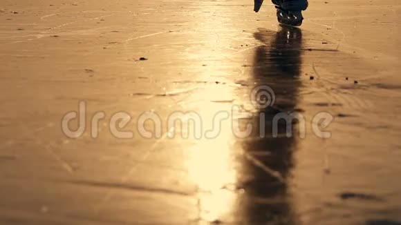 一个男孩在冬天的阳光下在湖上冰上滑冰的剪影慢动作视频的预览图