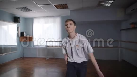 一个穿着牛仔裤和白衬衫的年轻人在教室里跳舞美丽的男人就像视频的预览图