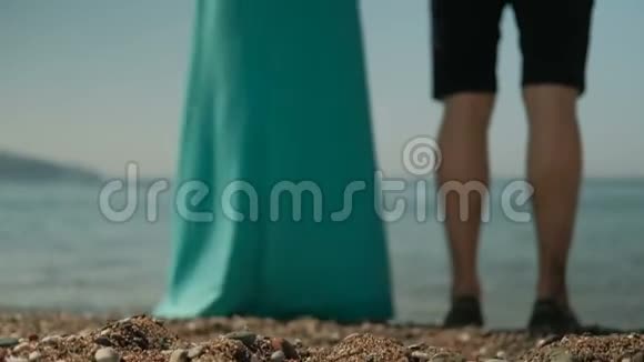 男人和女人穿着长裙双手站在海滩上他们握着手视频的预览图