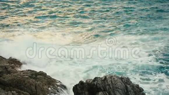日落时分海浪拍打在岩石海岸上视频的预览图