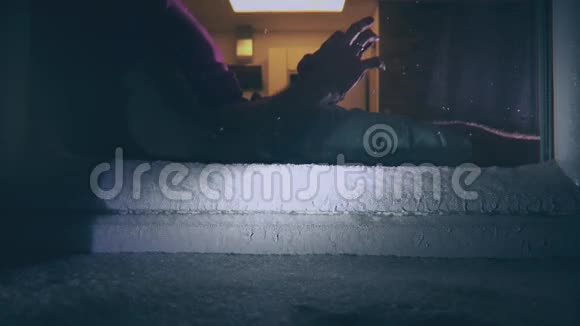 一个人坐在霜雪的窗户附近用他的智能手机视频的预览图