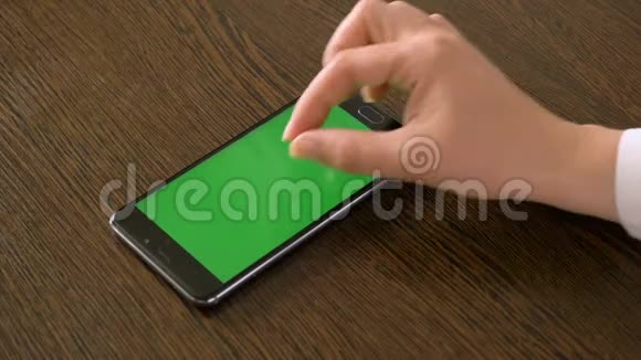 一只女手和一部手机上面有一个绿色的屏幕躺在桌子上视频的预览图