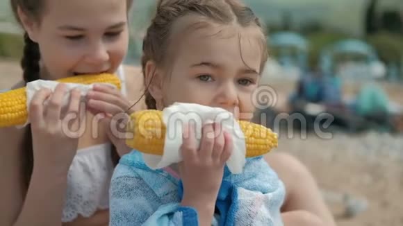 夏天的两个女孩用餐巾纸吃煮玉米视频的预览图