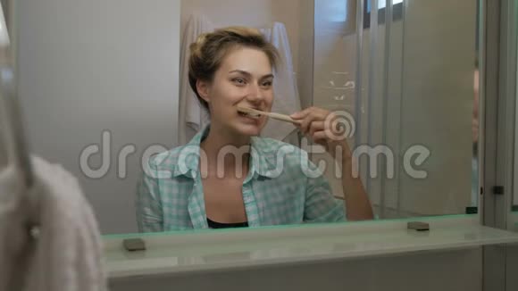 年轻女子刷牙早上站在室内的浴室里视频的预览图