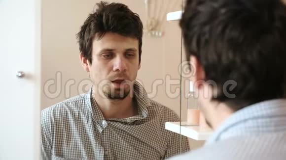 刚醒来的疲惫的男人看着镜子里的倒影看到他邋遢的样子穿着视频的预览图