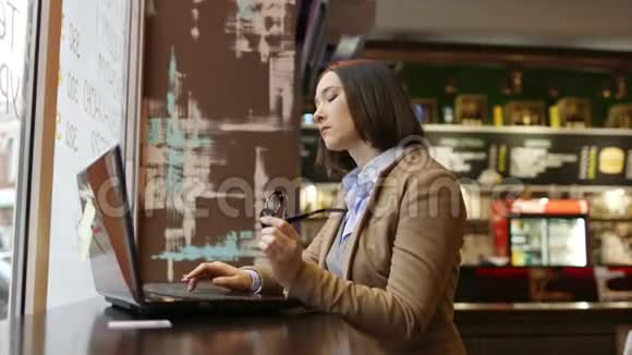 橱窗旁咖啡厅使用智能手机的年轻女性画像视频的预览图